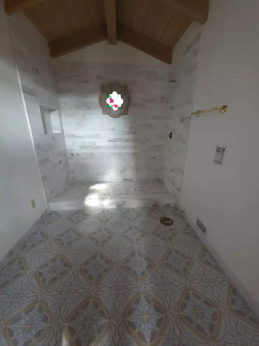 Bright tiled room in Bullhead City with patterned flooring, wooden ceiling, gold towel bar, and expert tile installation.