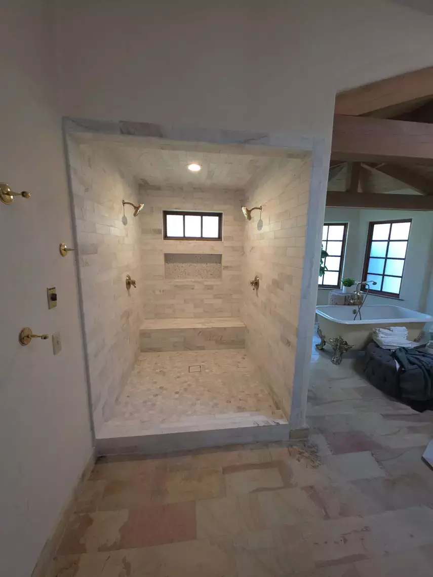 A walk-in shower with dual heads, built-in bench, and tiled walls upgrades this Bullhead City bathroom remodel.