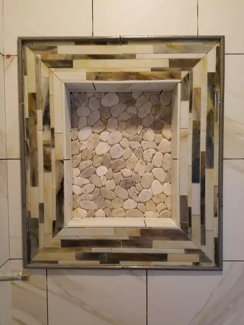 Recessed shower niche with pebble stone back and mosaic frame in marble tile—ideal for Bullhead City bathroom remodel.