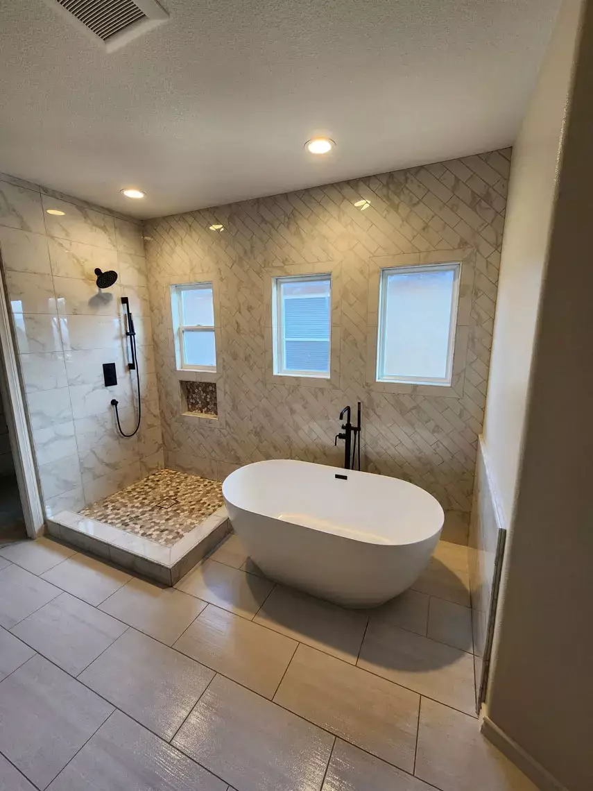 Modern bathroom in Bullhead City with freestanding tub, walk-in shower, black fixtures, beige tile—remodel inspiration.