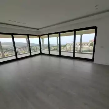 All Surfaces Flooring (1) Spacious room in Fort Mohave with floor-to-ceiling windows, gray tile flooring, and views of the balcony and landscape.