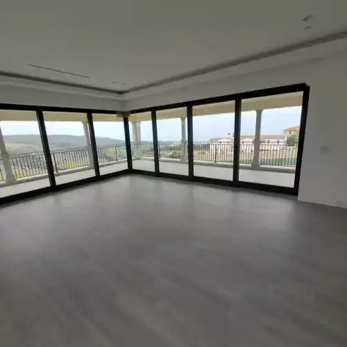 Spacious room in Fort Mohave with floor-to-ceiling windows, gray tile flooring, and views of the balcony and landscape.
