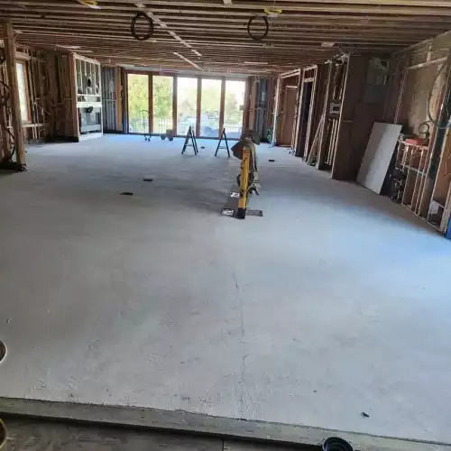 A spacious room in Fort Mohave with exposed beams, unfinished walls, new concrete floor—ideal for a kitchen installation.
