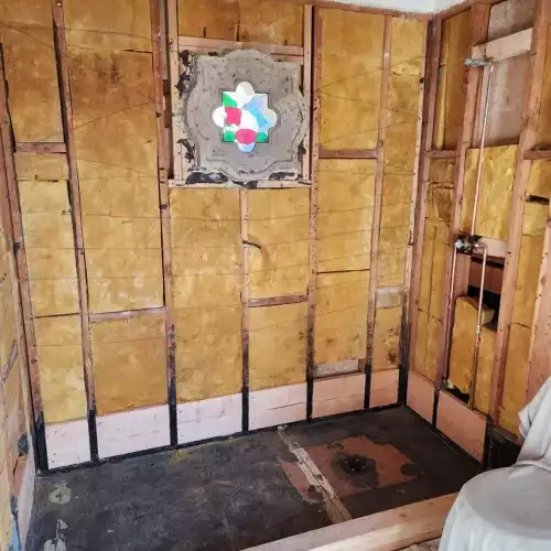 Partially demoed bathroom remodel in Fort Mohave with exposed studs, tiled floor, stained glass window; ready for flooring.