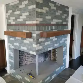 All Surfaces Flooring (4) Double-sided corner brick fireplace with green and white tiles, wood mantels, and new vinyl flooring in Bullhead City remodel.