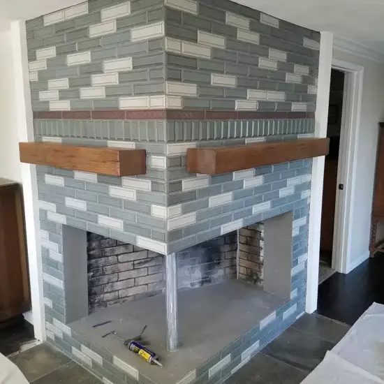 All Surfaces Flooring (4) Double-sided corner brick fireplace with green and white tiles, wood mantels, and new vinyl flooring in Bullhead City remodel.